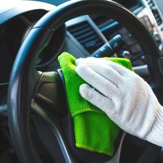 a gloved hand cleaning the steering wheel of a car