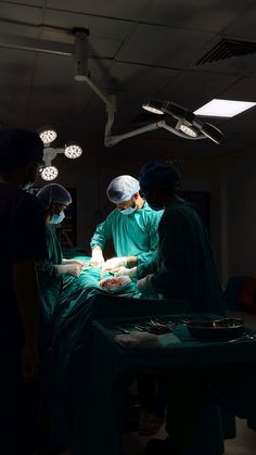 three surgeons performing surgery on a patient in an operating room with lights overhead and medical equipment hanging from the ceiling