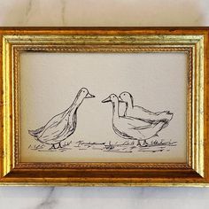 two ducks are standing next to each other in front of a marble wall with gold frame