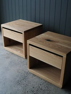 two wooden tables sitting next to each other on the ground in front of a wall