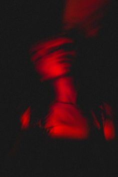 blurry image of two people in the dark with red lights on them and one person holding his arm out