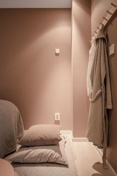 a bed with two pillows on top of it next to a wall mounted coat rack