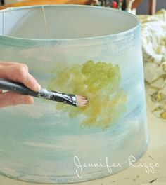 a person is painting a lamp shade with watercolors on the inside and outside