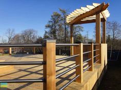 a wooden deck with metal railings and a pergolated area in the background