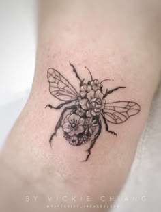 a black and white photo of a bee with flowers on it's back leg