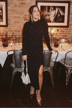 a woman standing in front of a table with chairs and pictures on the wall behind her