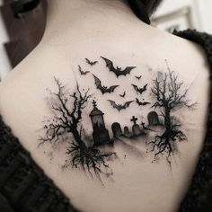 a woman's back shoulder tattoo with bats flying over the cemetery and graveyard on it