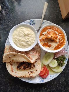 a plate with tortillas, sauce and cucumbers is on the table