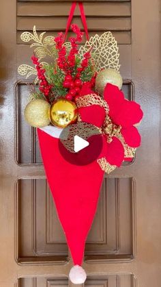 a red and gold christmas decoration hanging on the front door with an ornament