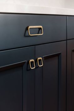 a black cabinet with brass handles and knobs on the doors is seen in this image