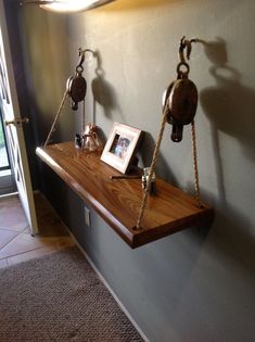 two old fashioned telephones are hanging on the wall next to a shelf with pictures