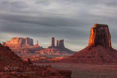 the desert is full of red rocks and tall rock formations, as well as clouds in the sky