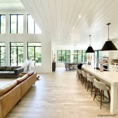 a large open living room and dining area with wood flooring, white walls and high ceilings