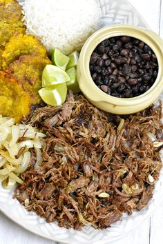 a white plate topped with meat, rice and beans