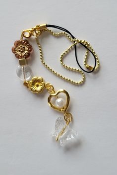 a necklace with two charms attached to it on a white surface and one has a flower