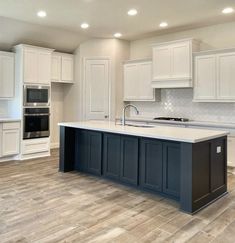 an empty kitchen with white cabinets and wood floors