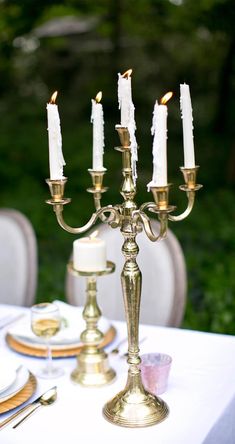 a candelabra with lit candles is on a table in the middle of an outdoor setting