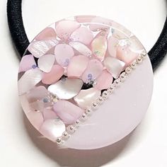 a close up of a necklace on a white surface with pink flowers and pearls in the center