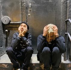 two young men sitting on steps with their hands to their faces