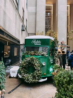 an old green bus with wreaths on the front and side is parked in front of a building