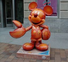 a statue of mickey mouse on the sidewalk