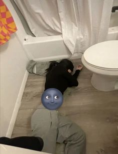 a person laying on the floor next to a toilet