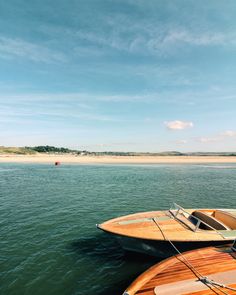 two boats are docked in the water on a sunny day with blue sky and white sand