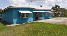 a blue house with white awnings on the roof and grass in front of it