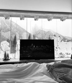 black and white photograph of a bedroom with a large window looking out at the mountains