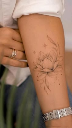 a woman's arm with a flower tattoo on the left side of her arm