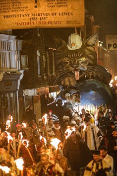 a large group of people with torches in front of a cat on top of a ball