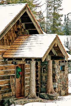 a small log cabin with a wreath on the door and two trees in front of it