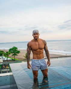 a shirtless man standing in the middle of a pool with his hands on his hips