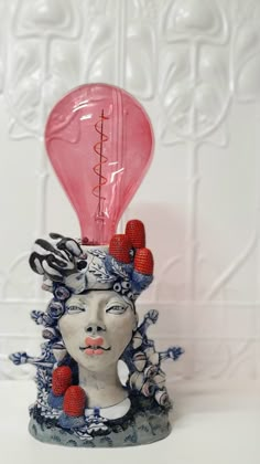 a ceramic sculpture with a pink light bulb in the shape of a woman's head