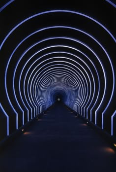 a long tunnel with blue lights in the middle and black walls on both sides that lead into another tunnel