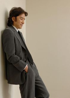 a man in a suit leaning against a wall