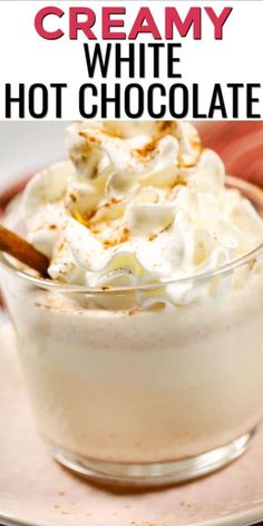 a glass bowl filled with hot chocolate and whipped cream on top of a white plate