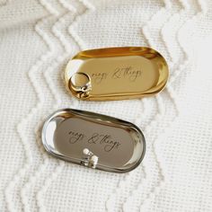 two gold and silver wedding rings are on top of a white blanket with the words, happy & merry written on it