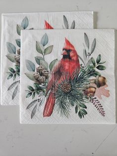 two napkins with red birds and pine cones on them, sitting next to each other