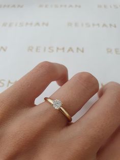 a woman's hand with a diamond ring on top of her finger, next to a sheet of paper