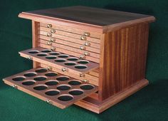 a wooden box with several compartments on the bottom and two rows of holes in it