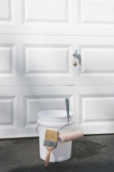 a paint bucket and brush sitting in front of a garage door