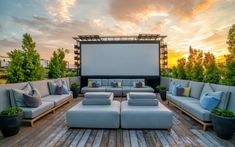 an outdoor seating area with couches, pillows and a projector screen in the background