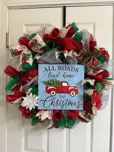 a christmas wreath with a red truck and evergreens on it that says all roads lead home for christmas