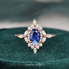 an engagement ring with a blue stone surrounded by white and pink diamonds on green velvet