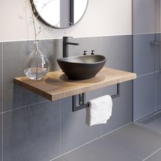 a white bowl sink sitting on top of a wooden counter next to a bathroom mirror