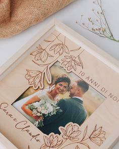 a wooden frame with an image of a bride and groom on it, next to some flowers