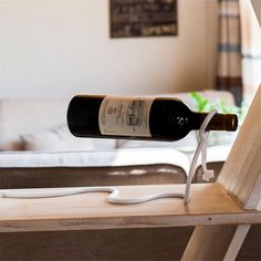 a bottle of wine sitting on top of a wooden shelf next to a white couch