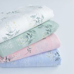 four folded sheets stacked on top of each other in different colors and patterns, all with floral designs