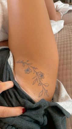 a woman's arm with a flower tattoo on it, sitting on a bed